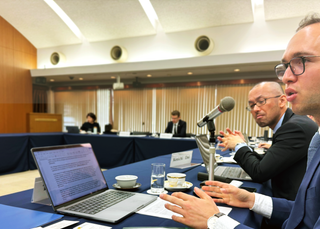 Person talking at a roundtable discussion.